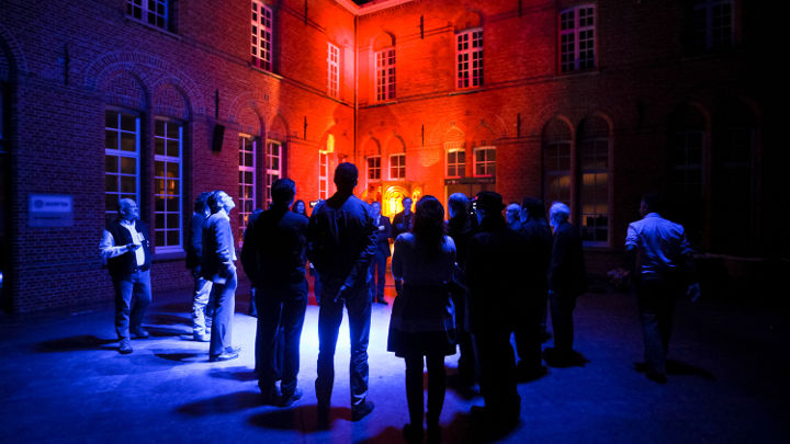 在飛利浦舉辦的工作坊中，一大群人在比利時 Turnhout 一棟室外照明美輪美奐的大樓外進行討論