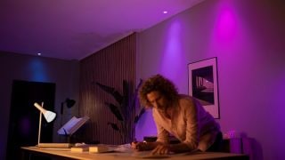 Philips Hue 智慧 LED 燈在客廳營造出充滿活力的紫色和粉紅色氛圍，為現代家庭的電影之夜和放鬆展示可客製化的氛圍照明。