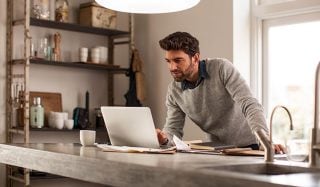 男士在光線充足的家庭辦公室中使用筆記型電腦並配備 LED 專用照明，以實現高效的遠端工作設定。